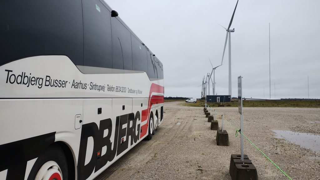 Turistbus foran vindmøller.